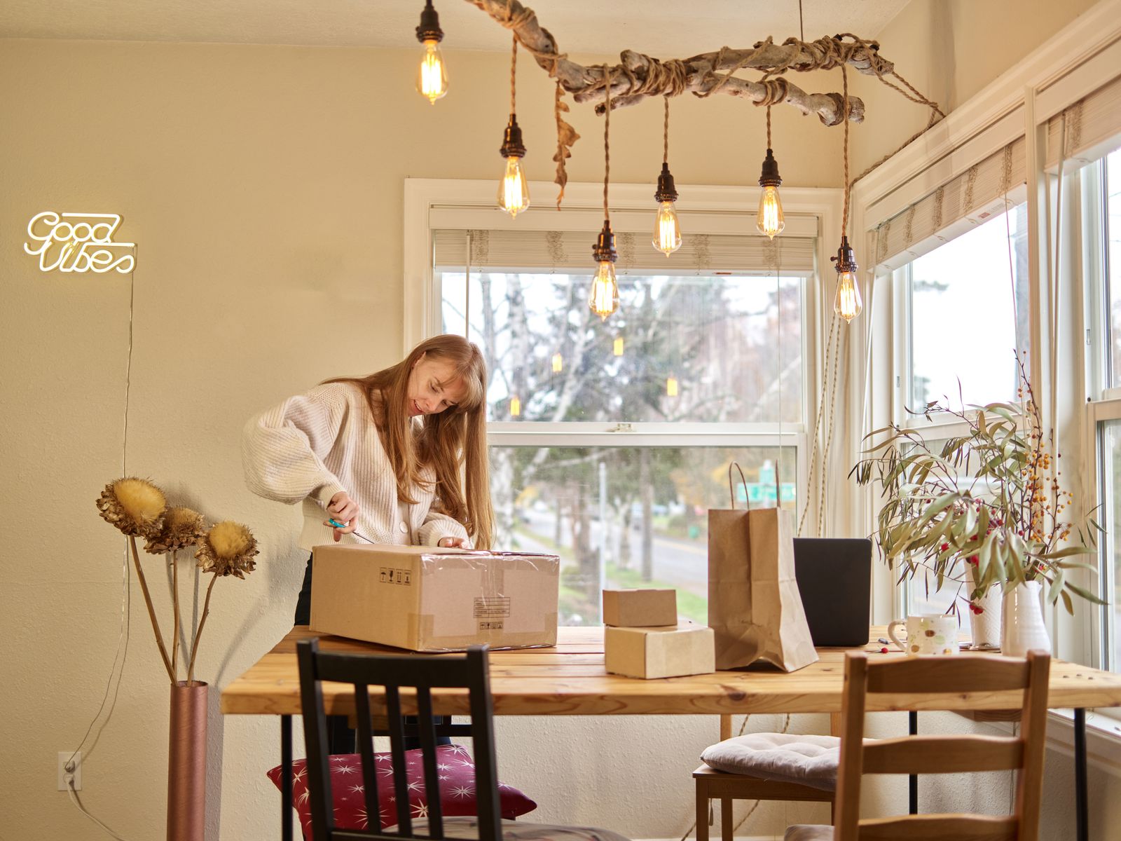 Woman carefully opening a delivery box on a wooden table at home.