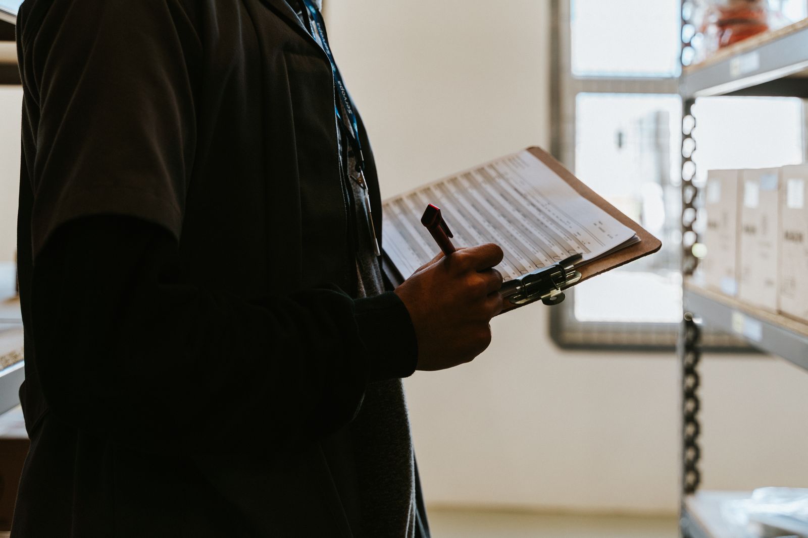 A person writing a checklist for goods and quantities.